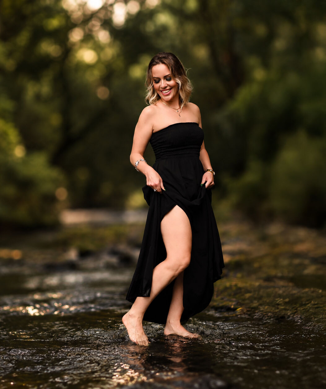 Denise junto ao riacho, com vestido preto